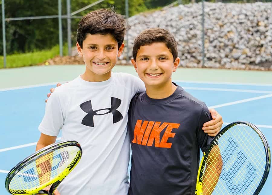 2 young boys holding tennis rackets