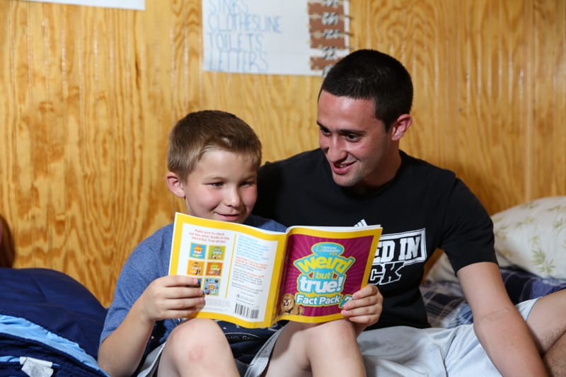 camp counselor with camper reading