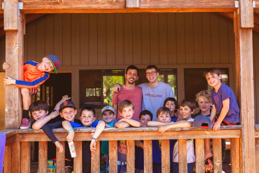 Group of campers and counselors on the porch of a cabin